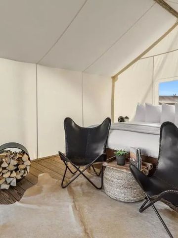 Innenansicht eines Luxuszeltes mit Bett, Sesseln und Holzdekoration