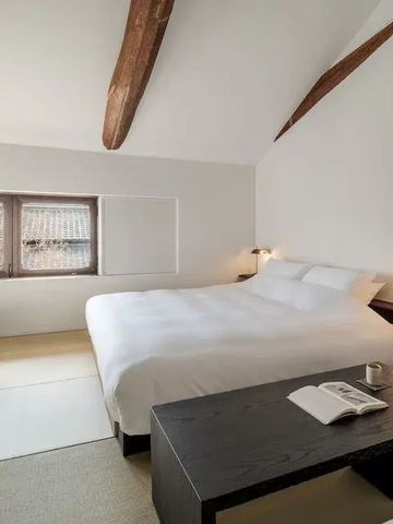 Geräumiges Hotelzimmer mit Dachbalken, großem Bett und Arbeitsbereich