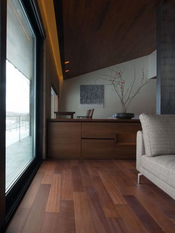 Helles Zimmer mit Holzböden und großen Fenstern mit Blick nach draußen.