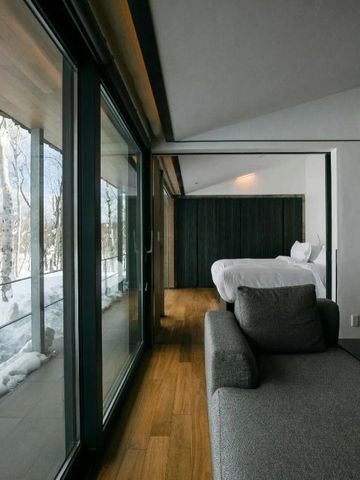 Gemütliches Schlafzimmer mit Blick auf verschneite Waldlandschaft.