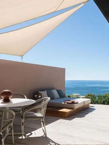 Terrasse mit Meerblick und stilvollen Möbeln unter einem Sonnensegel