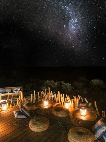 Outdoor-Ruhebereich bei Nacht unter sternenklarem Himmel mit Laternenlicht.