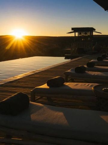 Sonnenuntergang am Infinity Pool mit Liegen auf einer Holzterrasse.