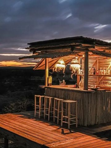 Kleine Outdoor-Bar aus Holz im Abendlicht mit Sitzgelegenheiten.