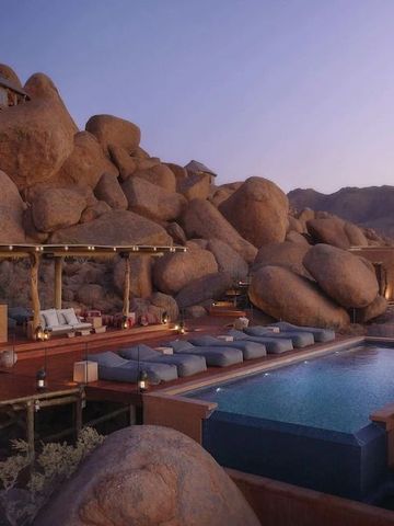 Luxuriöser Pool mit Felsenlandschaft bei Sonnenuntergang