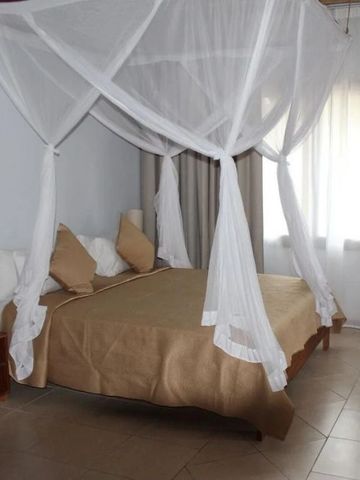 Schlafzimmer mit Moskitonetz über dem Bett und warmem Licht