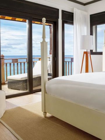 Geräumiges Hotelzimmer mit großem Bett und Balkon mit Meerblick