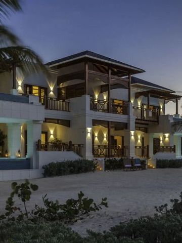 Beleuchtete Hotelvilla bei Dämmerung mit Palmen und Sandstrand