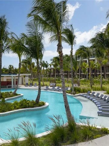 Geschwungener Pool umgeben von Palmen und Liegestühlen