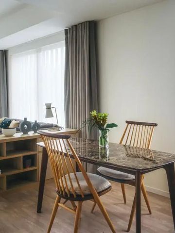 Gemütlicher Essbereich mit Holztisch und Stühlen vor großen Fenstern im Zimmer