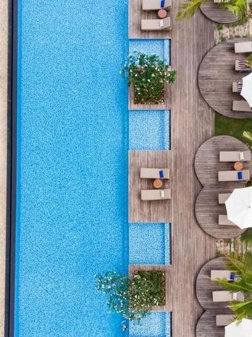 Blick von oben auf Pool mit Liegestühlen und Sonnenschirmen