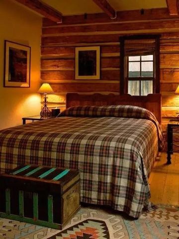 Schlafzimmer mit kariertem Bettbezug, Holzwänden und warmem Licht