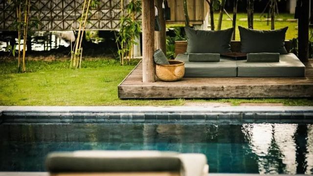 Entspannungsbereich mit grünen Kissen und Pool auf Holzboden