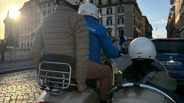 Dreiköpfiges Vespa-Team bei Sonnenuntergang auf einer gepflasterten Straße.