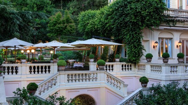 Eleganter Gartenbereich mit Treppen und Terrassen flankiert von grüner Vegetation.