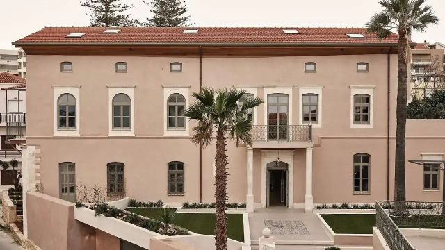Historische rosafarbene Hotelfassade mit Freitreppe und Palme im Eingangsbereich