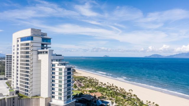 Außenansicht des modernen Hotelgebäudes am langen Sandstrand und Meer.