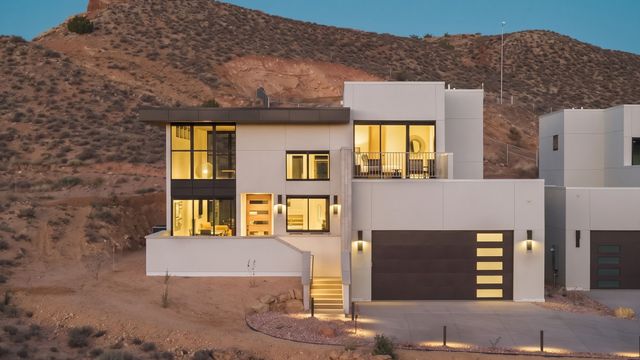 Moderne zweistöckige Villa mit beleuchteten Fenstern vor einer felsigen Landschaft.