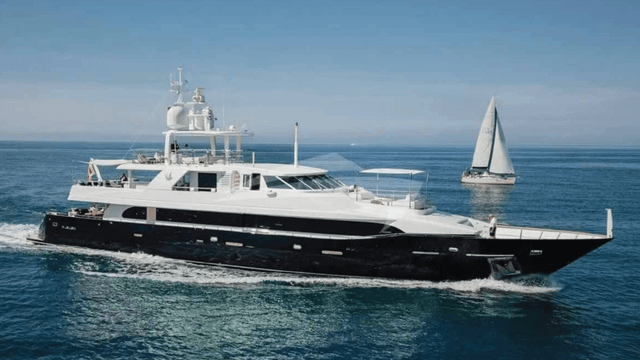 Elegante schwarze Yacht segelt neben kleinem Segelboot auf ruhigem Wasser
