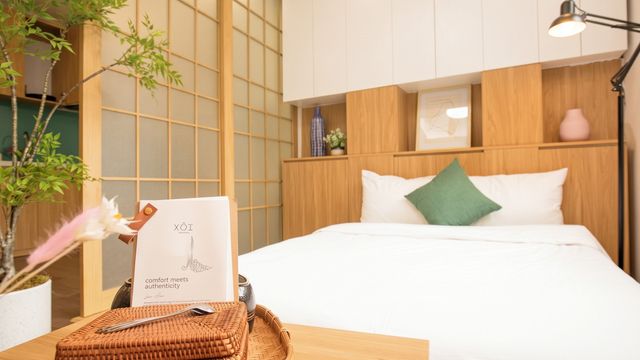 Helles Schlafzimmer mit Holzschiebetür, weißem Bett und Flechtkörben im Vordergrund.