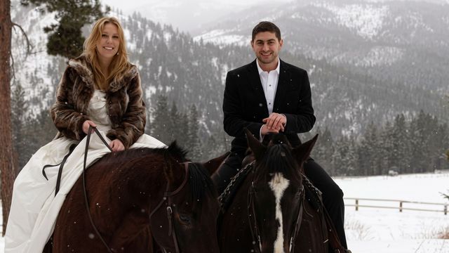 Ein Paar reitet auf Pferden durch eine verschneite Berglandschaft im Winter.