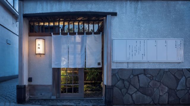 Eingangsbereich im traditionellen japanischen Stil mit weißen Stoffvorhängen und Wandlaterne.