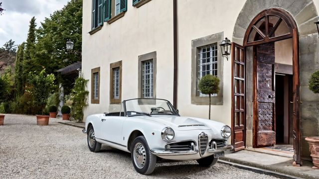 Weißer Oldtimer parkt vor der historischen Fassade des Anwesens mit grünen Fensterläden.