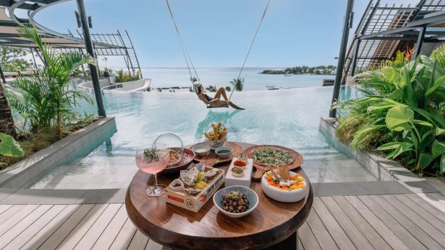 Gedeckter Tisch mit Gourmet-Gerichten vor Infinity-Pool und Meerblick mit Schaukel
