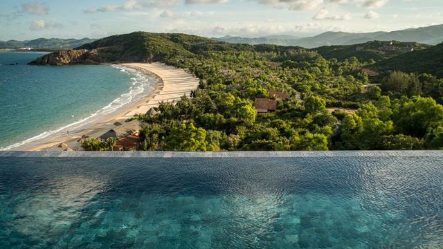 Infinity-Pool mit Blick auf unberührten Strand und grüne Landschaft
