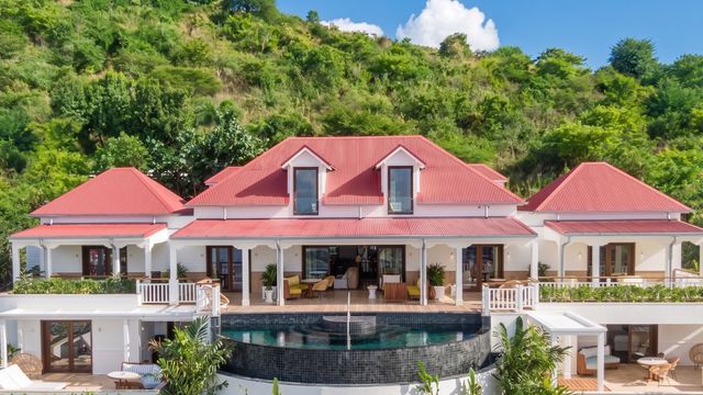 Villa mit Infinity-Pool und roten Dächern, umgeben von tropischer Landschaft.