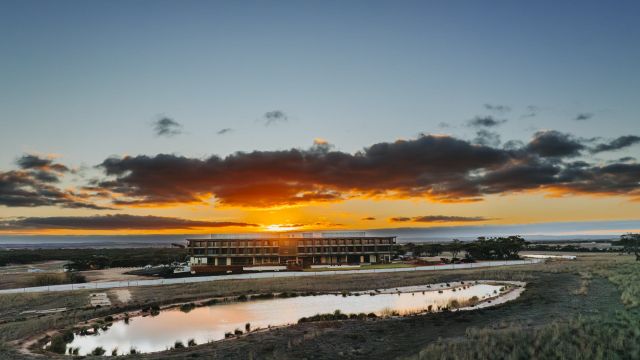 Monarto Safari Resort bei Sonnenuntergang, im Vordergrund eine Wasserstelle in der Savanne