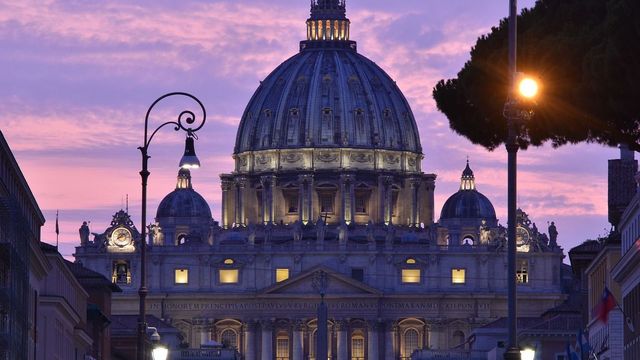 Beleuchtete Kuppel des Petersdoms im Abendlicht mit Wolkenhimmel