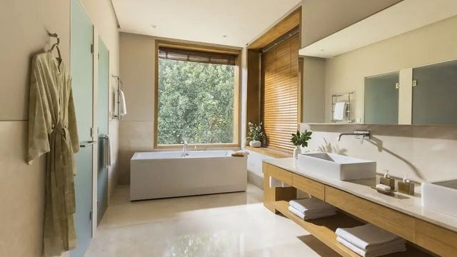 Helles Badezimmer mit freistehender Badewanne und großem Fenster zum Garten
