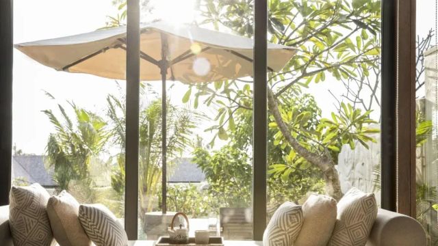 Gemütliche Sitzecke vor großen Fenstern mit Ausblick auf sonnigen Garten