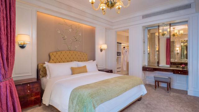 Luxuriöses Schlafzimmer im The St. Regis Singapore mit gelbem Kopfteil und edlem Kronleuchter