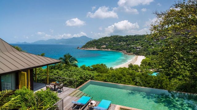 Infinity-Pool mit Sonnenliegen und Blick auf eine Bucht mit weißem Sandstrand und türkisblauem Wasser im Four Seasons Resort Seychelles