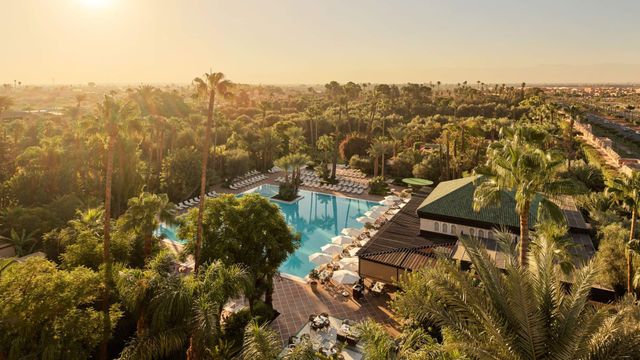 Das La Mamounia mit Blick auf den großen, eleganten Außenpool des Hotels, umgeben von Palmen, Liegestühlen und Gartenlandschaft.