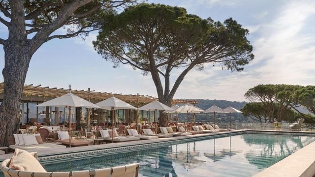 Pool des Hotels Lily of the Valley bei Saint-Tropez mit weißen Sonnenschirmen, eleganten Liegen und Blick auf die hügelige Mittelmeerlandschaft.