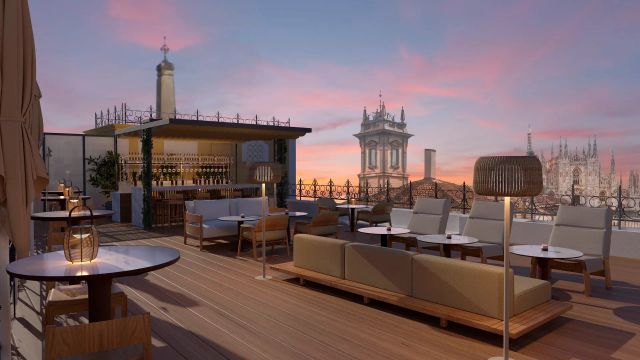Stilvolle Dachterrasse bei Sonnenuntergang mit eleganter Bar, modernen Loungemöbeln und Blick auf historische Gebäude sowie den Dom von Mailand im Hintergrund.