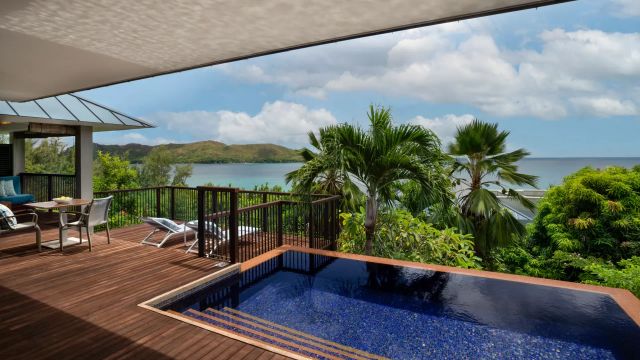Die Terrasse im Raffles Seychelles bietet einen privaten Pool mit Blick auf das Meer und grüne Hügel.