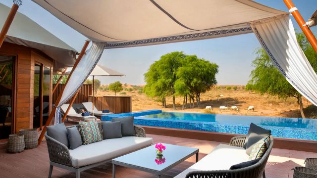 Exklusive Wüstenvilla im The Ritz-Carlton Ras Al Khaimah, Al Wadi Desert mit privatem Pool, schattiger Lounge und Blick auf eine weite Dünenlandschaft mit frei lebenden Oryx-Antilopen.