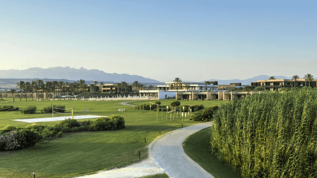 Blick vom Strand auf das weitläufige Verdura Resort – eingebettet in eine mediterrane Landschaft aus Palmen, Olivenhainen und sattem Grün. Die eleganten Zimmer und Suiten fügen sich harmonisch in die Natur ein.