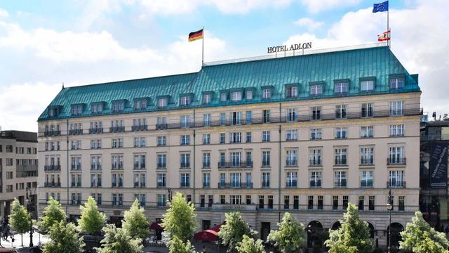 Historische Fassade des Hotel Adlon Kempinski Berlin mit grünen Dächern und Flagge.