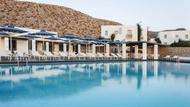 Moderner Poolbereich mit blauen Sonnenschirmen und Bergkulisse.