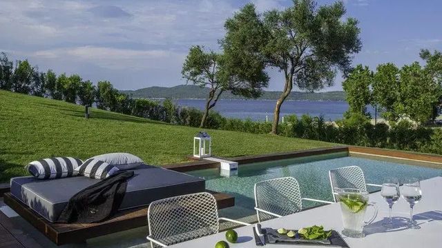Terrasse mit Infinity Pool und Meerblick umgeben von grüner Landschaft