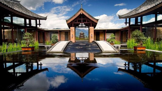 Traditionelle Architektur des Banyan Tree Lijiang mit Wasserspiegelung und Bergblick