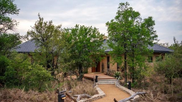Eingang zur Villa umgeben von üppiger Vegetation und Naturpfad
