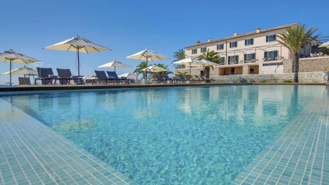 Klarer Pool mit Blick auf weißes Gebäude und Sonnenschirme