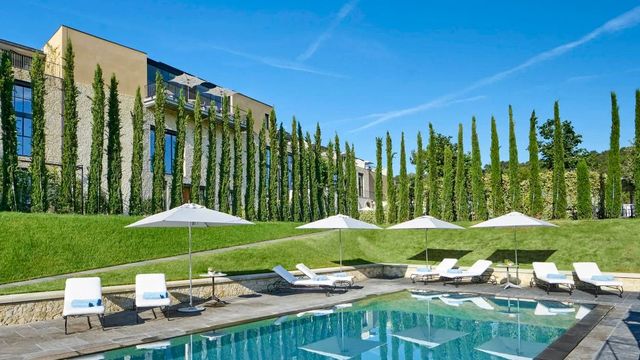 Grüne Gartenlandschaft mit Pool und Sonnenschirmen vor eleganter Architektur