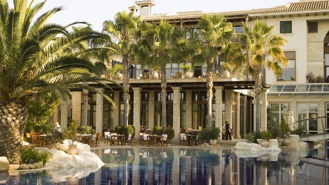 Eleganter Poolbereich mit Palmen und beeindruckender Fassade